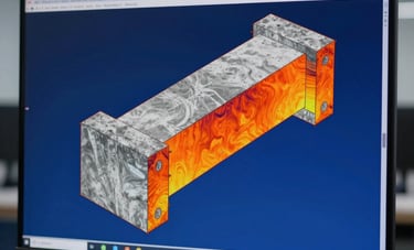 A close-up technical photograph of a computer monitor showing a Finite Element Analysis simulation. The structural model displays color gradients from deep blue to bright orange indicating stress distribution on a complex concrete beam. The background is a minimalist, dimly lit engineering office in Guadalajara. Technical precision and elegance.