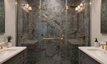 A sophisticated bathroom renovation in a North American residence, showcasing a glass-enclosed walk-in shower with charcoal grey tiling, a light silver vanity, and warm brass fixtures under elegant recessed lighting.