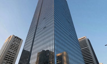 An architectural low-angle photograph of a modern glass skyscraper in a Brazilian business district like Paulista Avenue, reflecting the blue sky and surrounding cityscape, symbolizing corporate stability and growth.