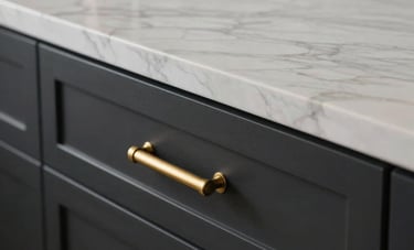 A detailed close-up shot focusing on premium kitchen textures: a polished white marble countertop meeting custom matte black cabinetry with brushed gold brass hardware, soft natural light, North American / US luxury interior.