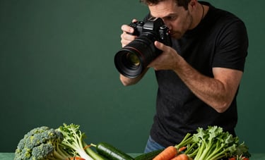 A professional food photographer in a North American restaurant setting up a high-contrast shot of vibrant vegetables on a Matte Forest Green background.