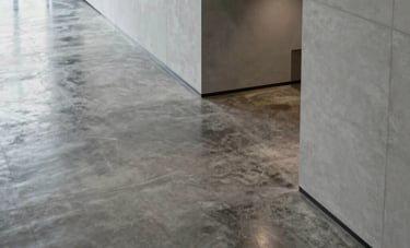 A high-angle photography shot of a minimalist, modern corporate lobby in the United States. Polished concrete floors and light gray walls reflect soft, professional lighting, conveying a sense of integrity, security, and innovation.