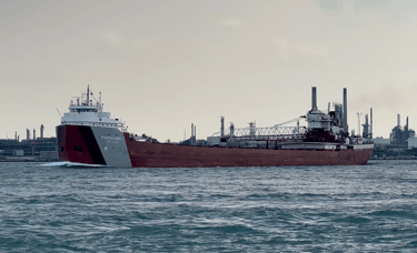 Classic forward pilothouse lake freighter Philip R. Clarke passing an oil refinery.