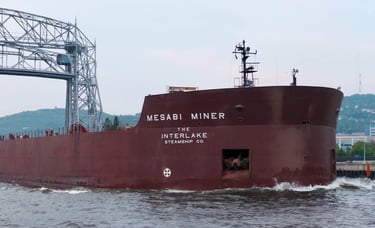 The bow section of the huge red ship Mesabi Miner passing through a narrow canal.