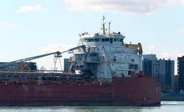 A close-up view of the aft section of a large red ship with a white superstructure.