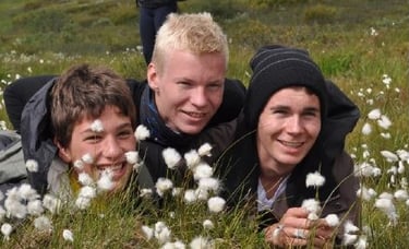 three smiling boys lying in a meadow-Telelaget