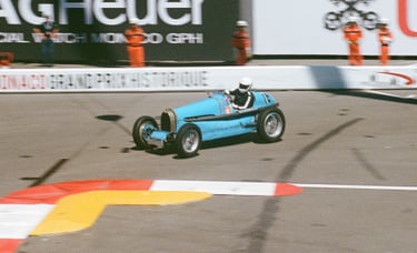 a man driving a blue race car on a track in Monaco