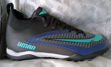 Zapatos de fútbol para césped artificial Uman en negro y azul con detalles en turquesa.