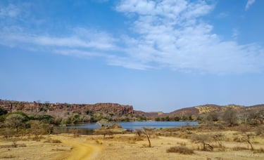 a dirt road with a lake and mountains in the background