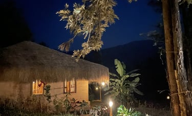 Night view of a rustic mud house with a thatched roof in Nelli Mud Village