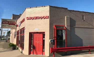 Exterior view of the Toledo New Bath Elite showroom featuring red trim, brick walls, and the main entrance on Bennett Road in