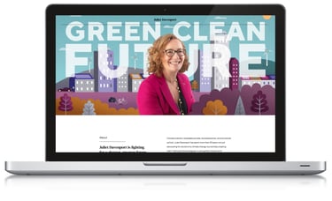 Web page with a woman sits in front of an illustrated scene of colourful a town on a laptop screen.
