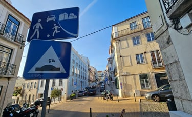 Street art sur panneau de signalisation représentant un tuk tuk sautant un dos d'äne à Lisbonne