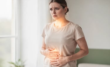 Donna con sintomi di tiroidite di Hashimoto, espressione affaticata e mani sull’addome gonfio