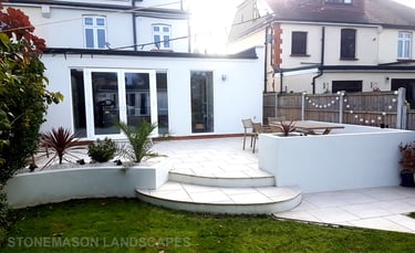 Modern chic raised porcelain patio with white rendered walls and planters