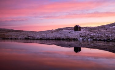 Lake near Nes on Eysturoy reflecting sunset sky and surrounding hills, calm and minimalist Faroe Islands landscape