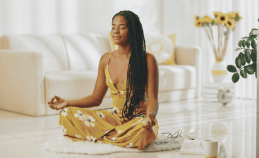 a woman sitting on a rug in a living room meditating
