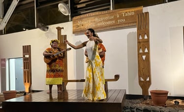 Tahitian dancers and musicians performing a welcome ceremony below a 'Tahiti welcomes you' sign