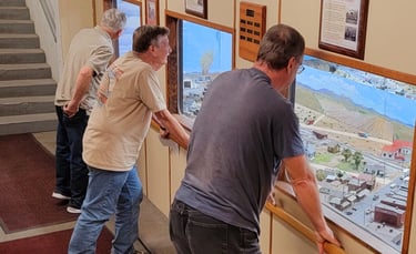 Viewing gallery windows with vistors looking at the model train layout