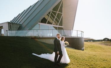 Bride and groom walking down a hill, wedding venue in the background, Canberra wedding photographer