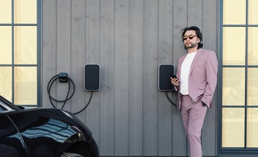 Laimingas elektra varomų automobilių krovimo stotelių savininkas žvelgia ir skaičiuoja santaupas