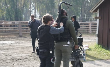 a man and woman are standing in a field working on an Easy Rig camera platform