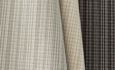 Textured woven upholstery fabric samples in neutral shades of beige, grey, and charcoal.