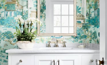 Elegant bathroom vanity with white marble top, white orchid plant, and teal chinoiserie wallpaper.