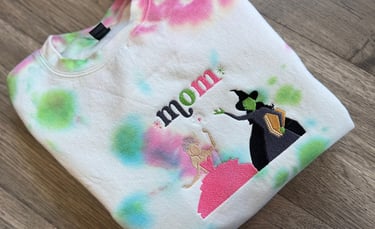 a white, pink and green tie dyed sweatshirt with the word "mom" embroidered on it
