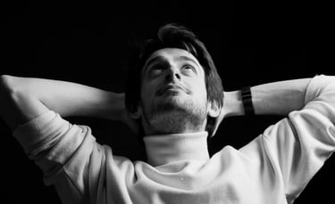 Un jeune homme décontracté les bras derrière les tête en photo noir et blanc de studio