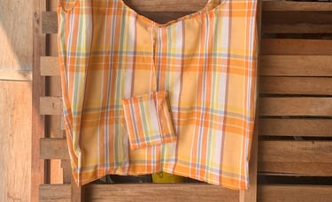 a handmade shopper bag in orange check with a small pouch attached hanging on a wooden pallet