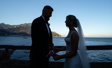 a bride and groom standing on a balcony overlooking the ocean