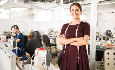 Una sastra sonriente con una cinta métrica en una fábrica de confección profesional