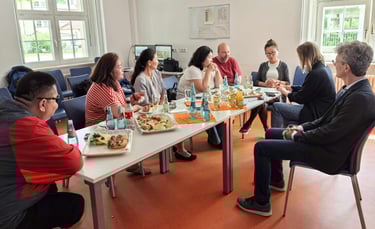 Diverse colleagues sharing lunch and snacks at a business meeting table in an office.