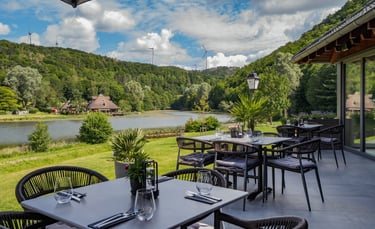 „Außenterrasse eines Seerestaurants mit Blick auf grüne Hügel und einen ruhigen See