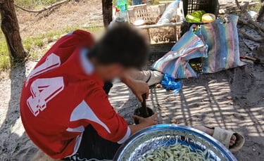 Photo d'un jeune accompagné par Bourokk et Kadiamor  en train d'aider à la préparation du repas