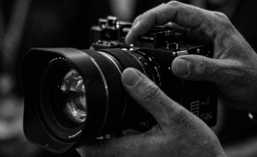 Extreme close-up of a focused crew member's hands adjusting a camera lens on a film set, moody low-key lighting, high-contrast monochrome with deep shadows, anamorphic lens, 35mm grain.