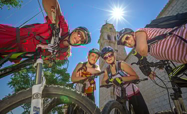 A group of cyclists in helmets posing for a photo during a sunny mountain bike tour.