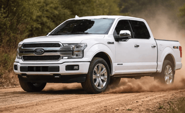 Ford F-150 branca andando em estrada de barro levantando poeira