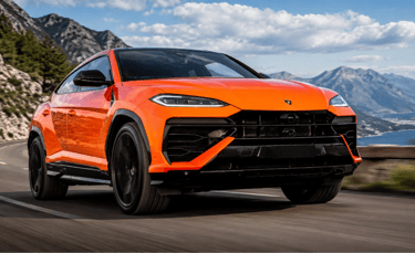 Novo Lamborghini Urus laranja sem placa dianteira em estrada montanhosa ao fundo