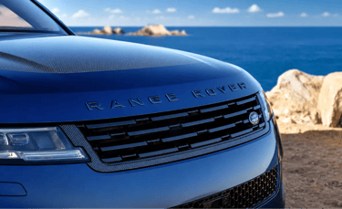 Range Rover azul em destaque com cenário costeiro ao fundo