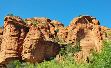 Sedona - golden sandstone rock formations in interesting shapes against the green foliage 