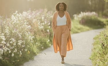 a woman walking down a path with a long coat