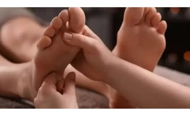 Terapeuta massageando o pé direito de uma paciente deitada na maca.