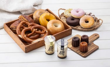 株式会社侍ファクトリーの各ブランド商品。木のテーブルにブレッツェル、ベーグル、プリン、カヌレなどが並ぶ様子|堺市のニュースならサカイタイムズ