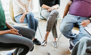 Personen sitzen in einem Kreis während einer Gruppentherapiesitzung.