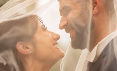 a bride and groom are standing in front of a veil
