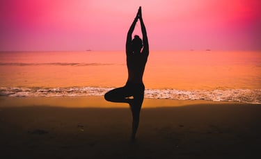 Silhouette of a woman practicing yoga on the beach at sunset