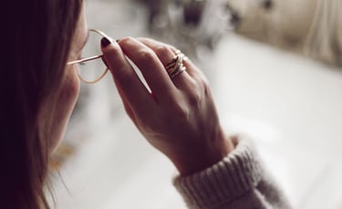 a woman in a sweater and glasses is holding a pair of glasses