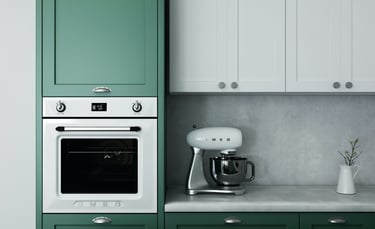 Cocina de diseño con armarios en tonos verde y blanco, electrodomésticos integrados y encimera gris.